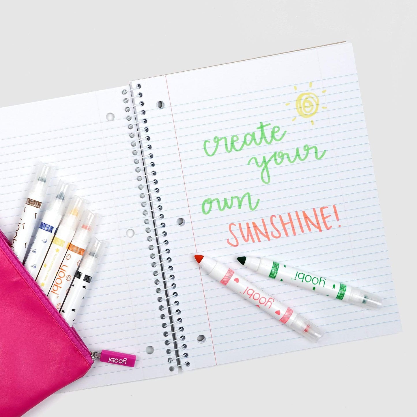 inside of open one subject spiral notebook showing college-ruled paper and 3-hole punch.  Shown with markers